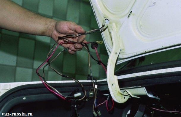 Извлечение жгута проводов из отверстия в багажнике
