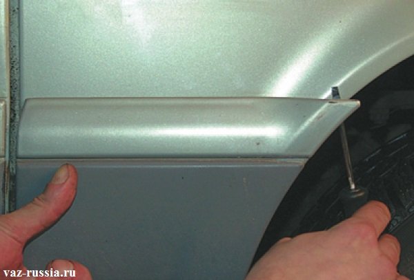 Снятие молдинга при помощи отвёртки, который располагается на переднем крыле автомобиля